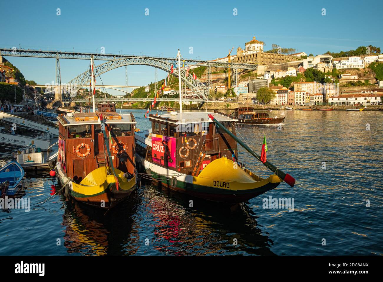 Zwei Ausflugsboote, die am Ufer des Douro-Flusses in Ribeira in Porto, Portugal, festgemacht wurden. Luís i Bridge ist im Hintergrund Stockfoto