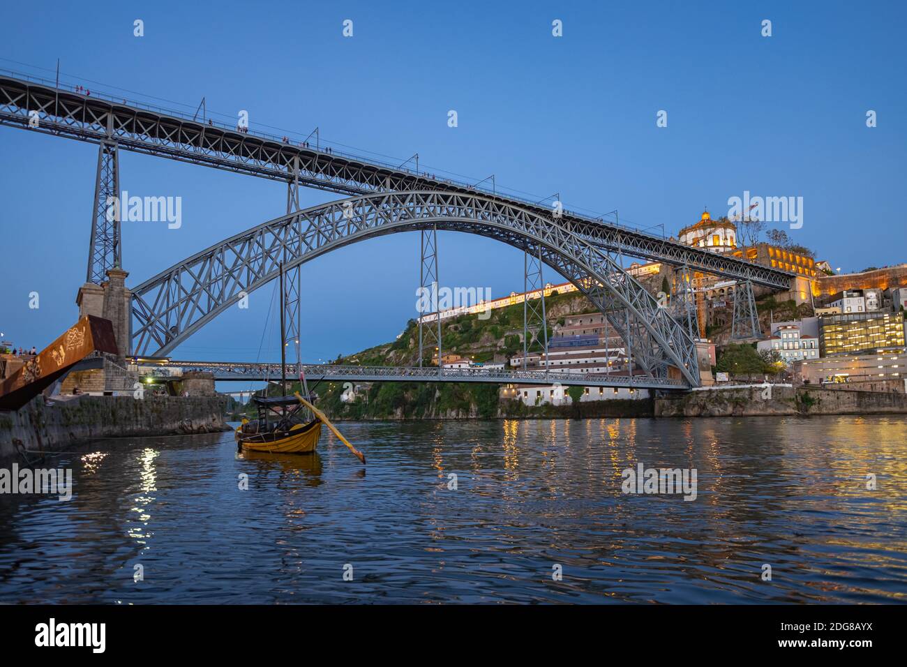 Niedriger Weitwinkelclip der Luis I Brücke bei Abenddämmerung in Porto, Portugal. Holzrabelo Boot im Vordergrund Stockfoto
