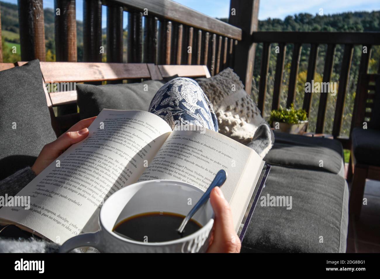 Lesen auf der Terrasse in der Sonne mit einer Tasse Kaffee Stockfoto