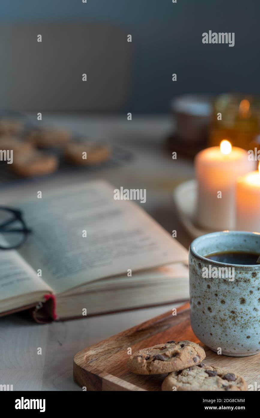 Lesebuch am gemütlichen Winterabend mit Kerzen, Tee und Keksen. Stockfoto