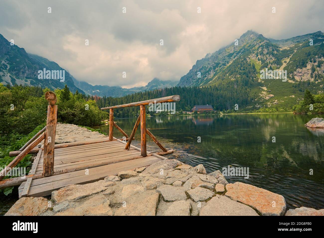 Fußweg und Holzbrücke am See hoch in den Bergen. Instagram-Effekt, Retro-Filter. Stockfoto
