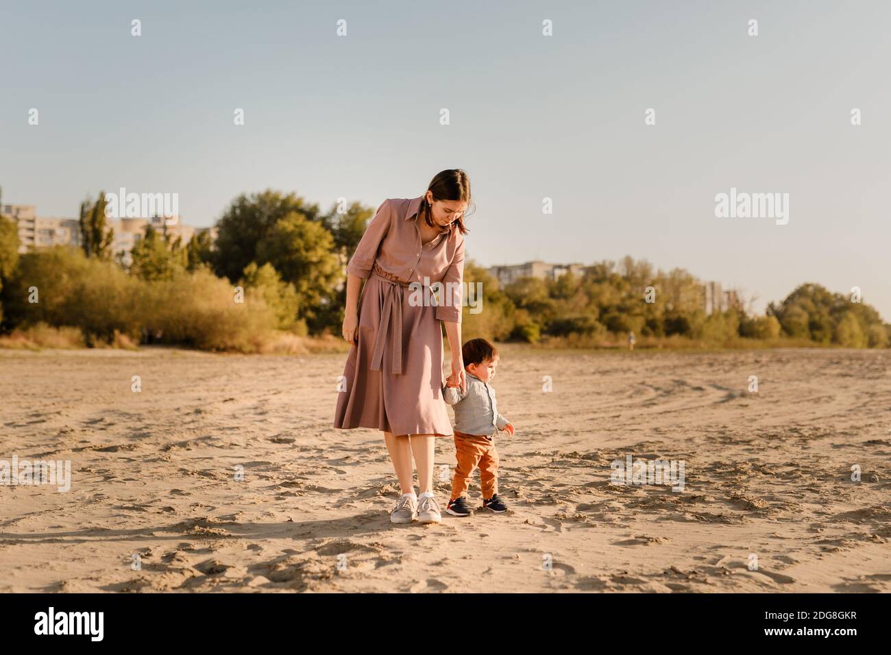 Portrait der liebenden Mutter und seines einjährigen Sohnes, der mit Sand läuft und spielt. Stockfoto