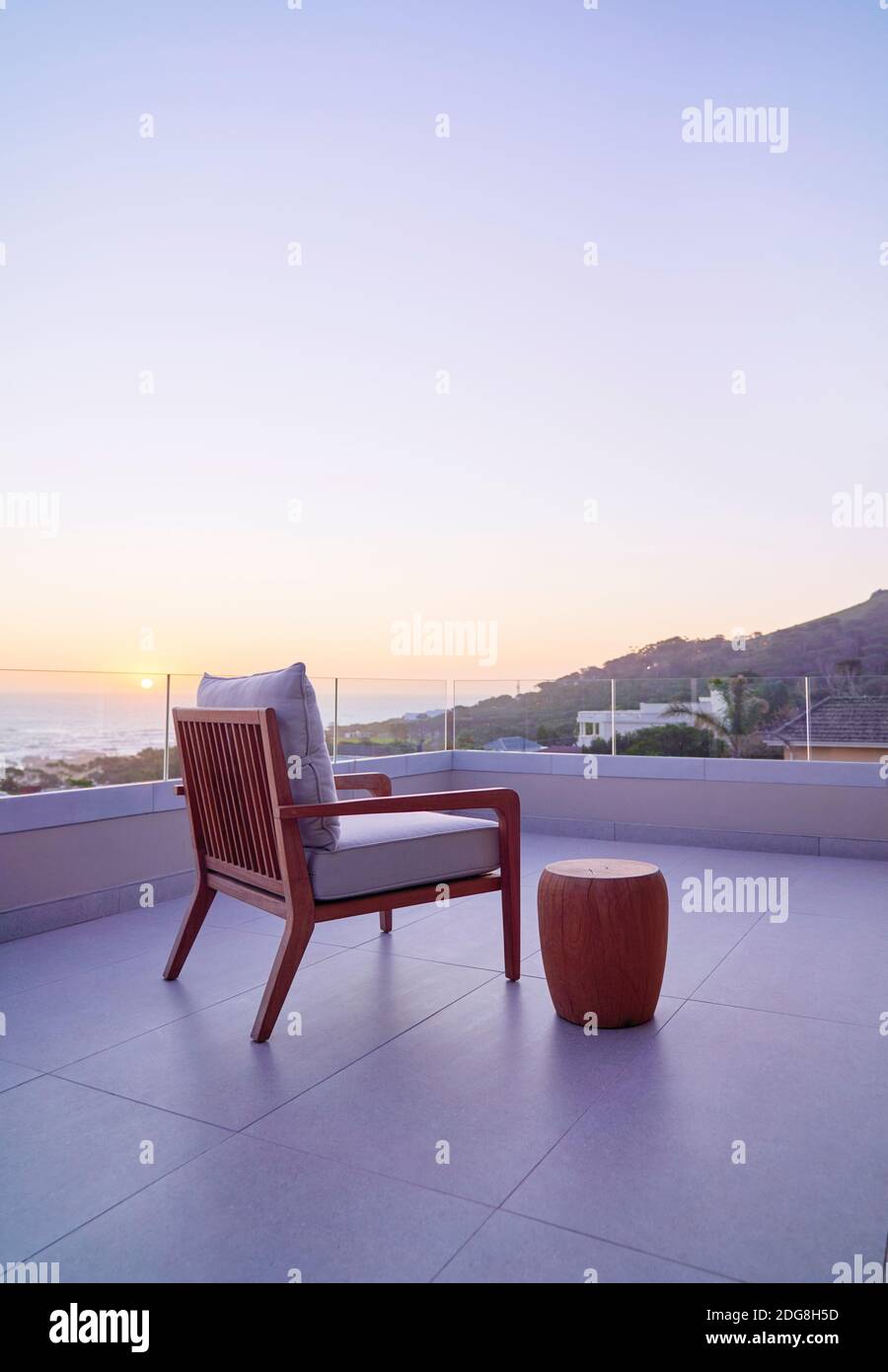 Sessel auf Luxusbalkon mit malerischem Blick auf den Ozean und den Sonnenuntergang Stockfoto