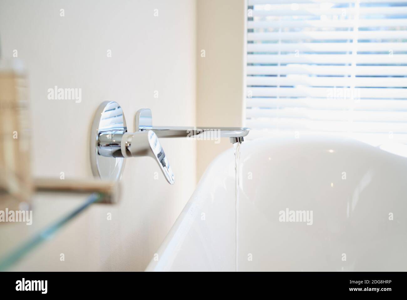 Schließen Sie das Wasser aus dem Wasserhahn, der die weiße Wanne einfüllt Badezimmer Stockfoto