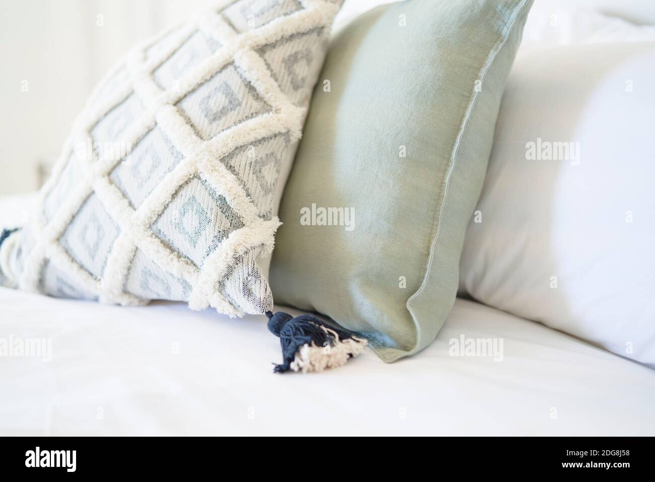 Dekoratives Nahtkissen mit Quaste auf dem Bett Stockfoto