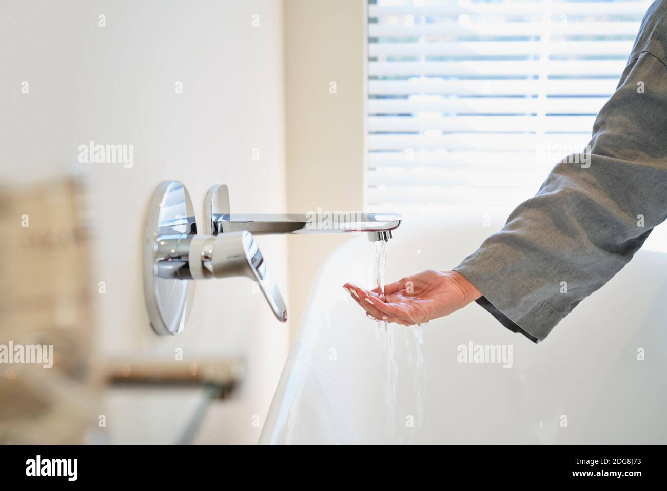 Frau überprüft die Wassertemperatur aus dem Wasserhahn der Badewanne im Badezimmer Stockfoto