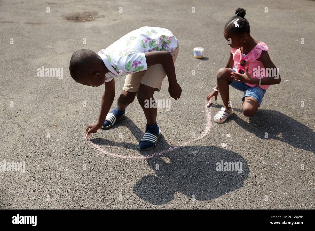 Bruder und Schwester spielen mit Bürgersteig Kreide auf sonnigen Bürgersteig Stockfoto
