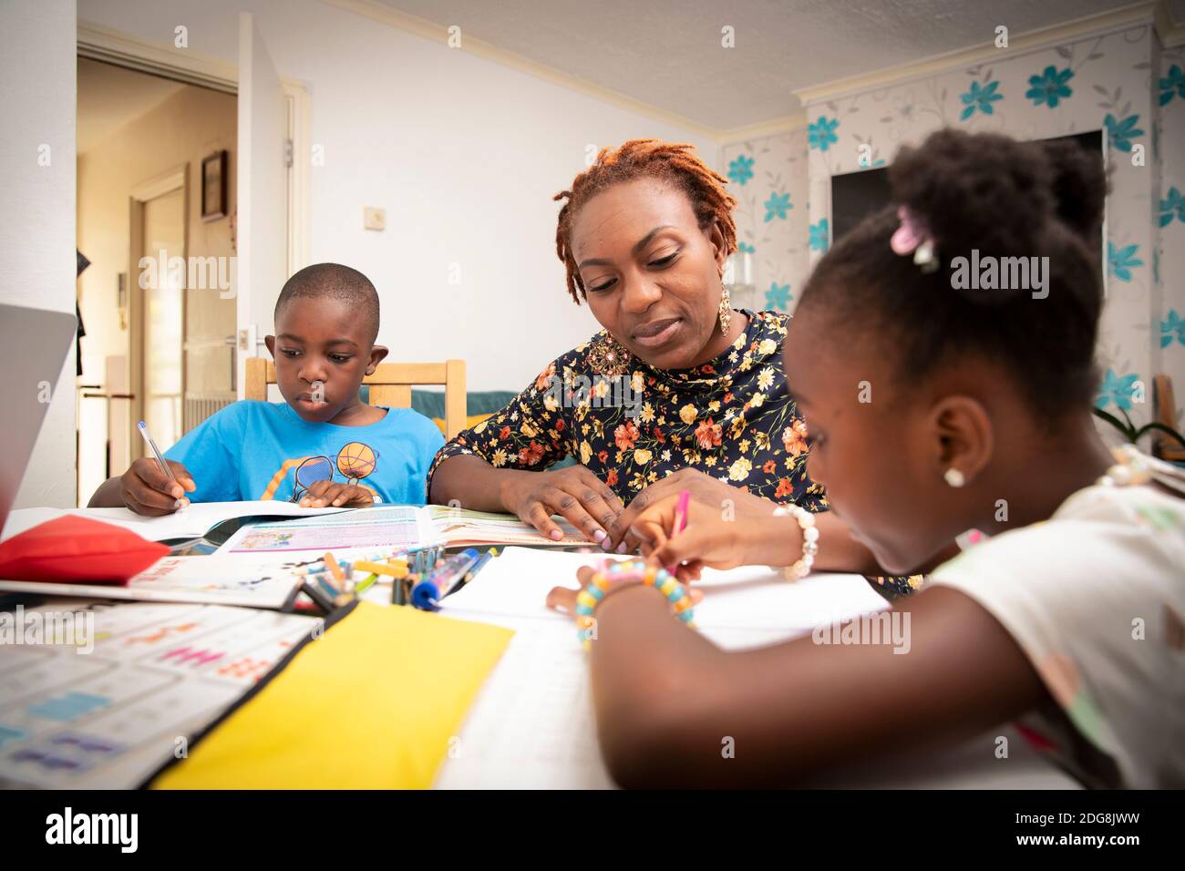 Mutter hilft Kindern mit Hausaufgaben am Esstisch Stockfoto