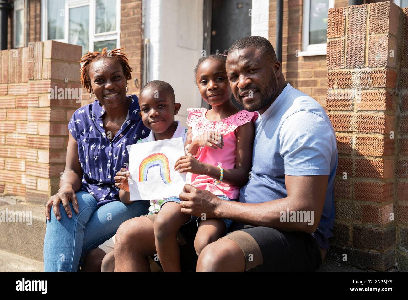 Portrait glückliche Familie mit Regenbogenzeichnung auf sonnigen Front stoop Stockfoto