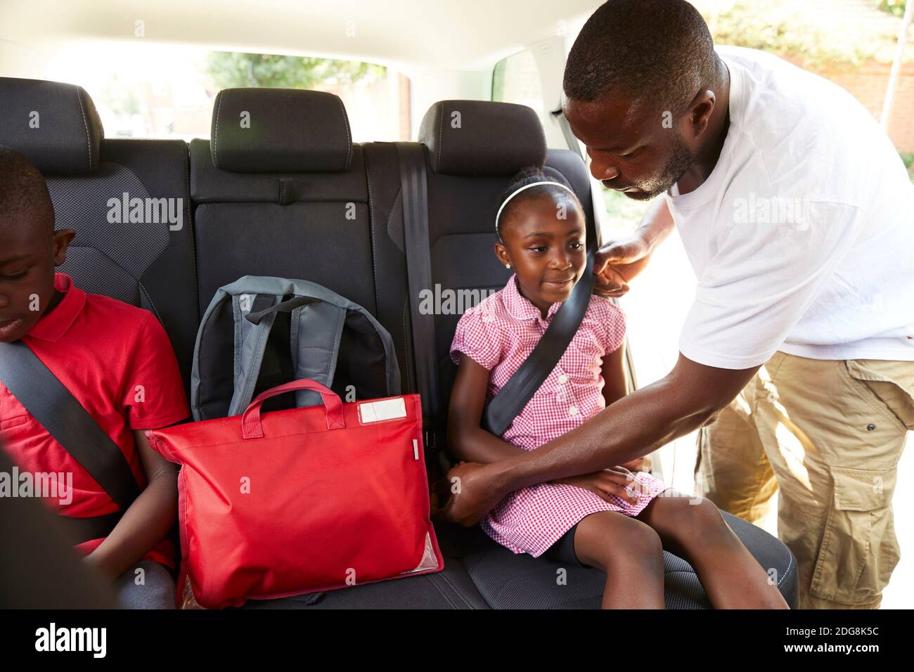 Vater Sicherheitsgurt für Tochter auf dem Rücksitz von Auto Stockfoto