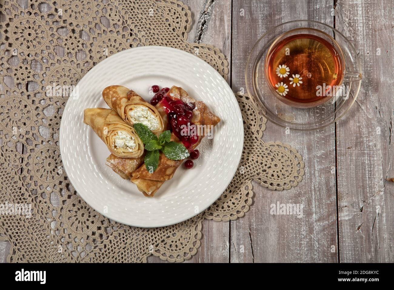 Mit Pfannkuchen mit Fleisch und Tasse Tee auf einem alten hölzernen Hintergrund Platte Stockfoto