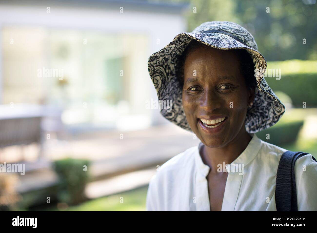 Portrait glücklich reife Frau in Sonnenhut im Sommer Hinterhof Stockfoto