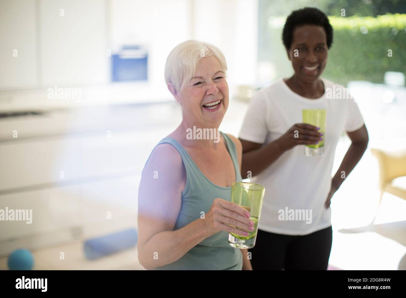 Glückliche ältere Frauen Freunde Trinkwasser nach dem Training zu Hause Stockfoto