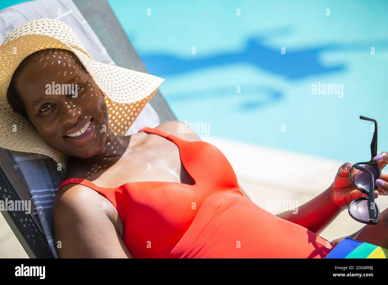 Portrait glücklich reife Frau in Sonnenhut Sonnenbaden bei sonnig Am Pool Stockfoto