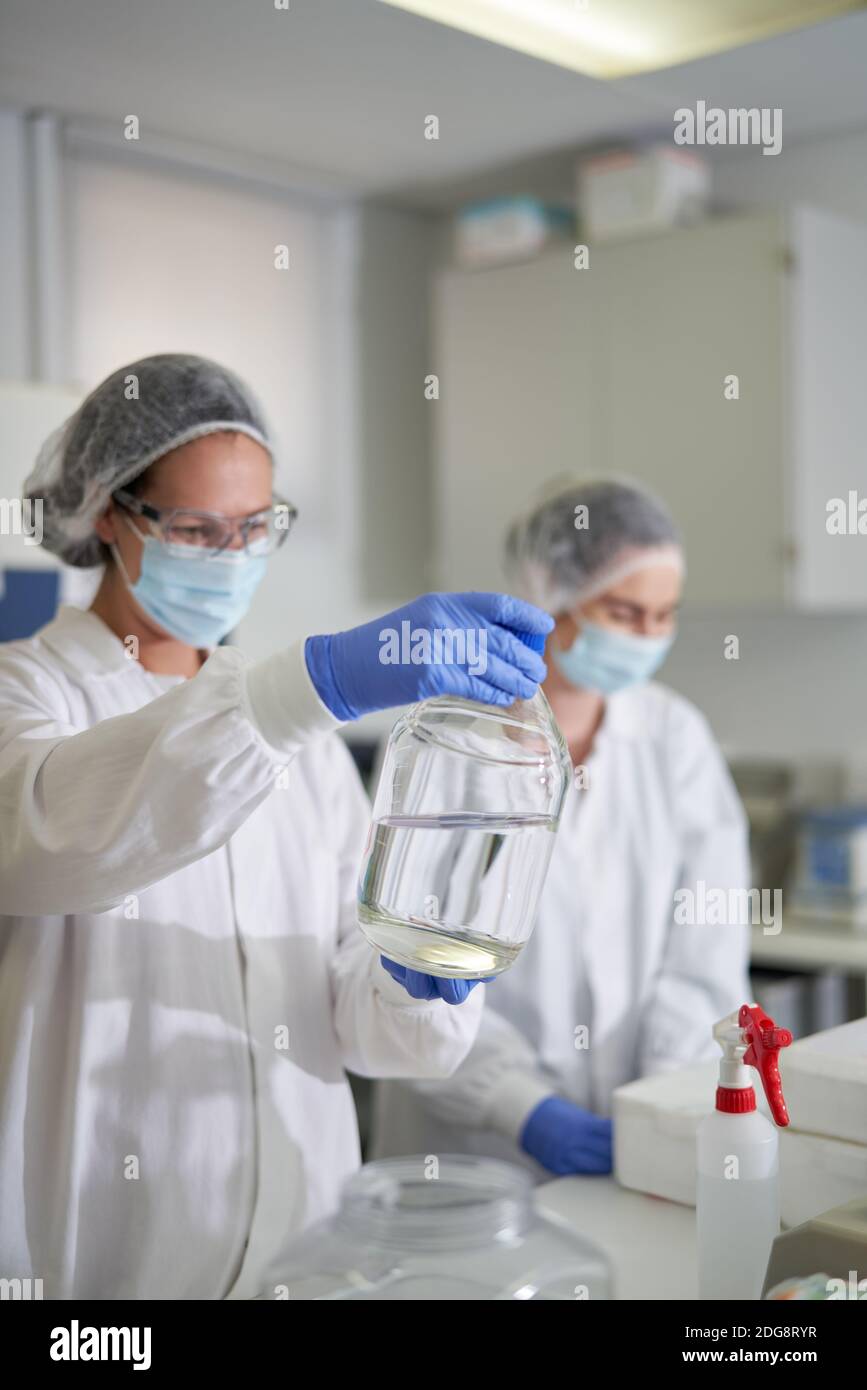 Wissenschaftler in Schutzkleidung Untersuchung Flüssigkeit im Labor Stockfoto