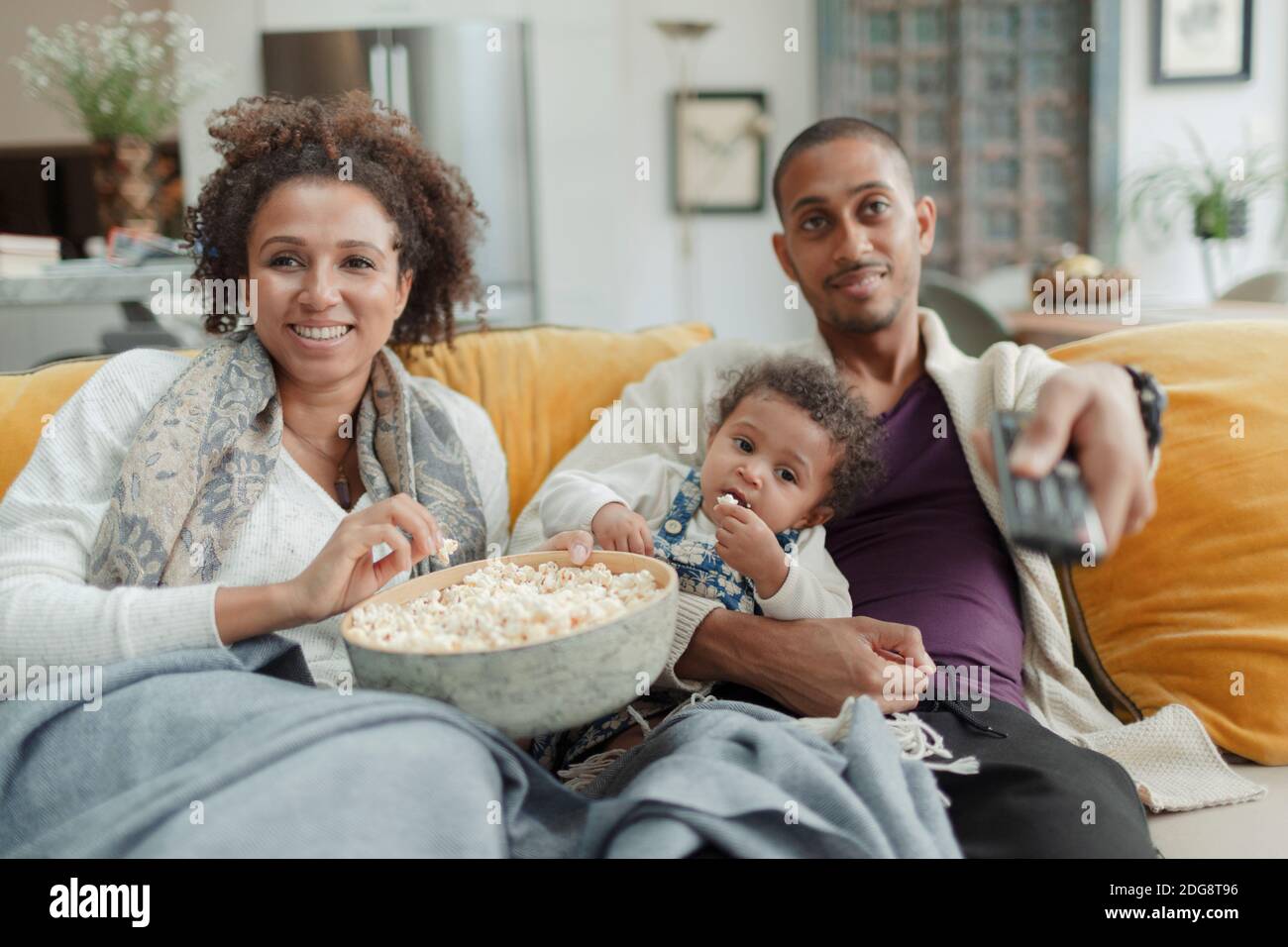Glückliches Paar mit Baby Tochter Fernsehen und Popcorn essen Stockfoto