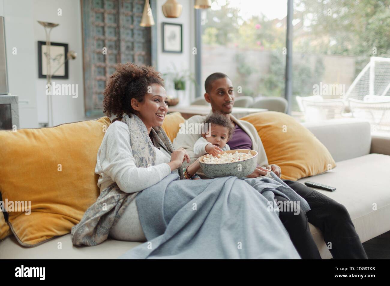 Eltern mit Baby Tochter beim Film mit Popcorn auf dem Sofa Stockfoto
