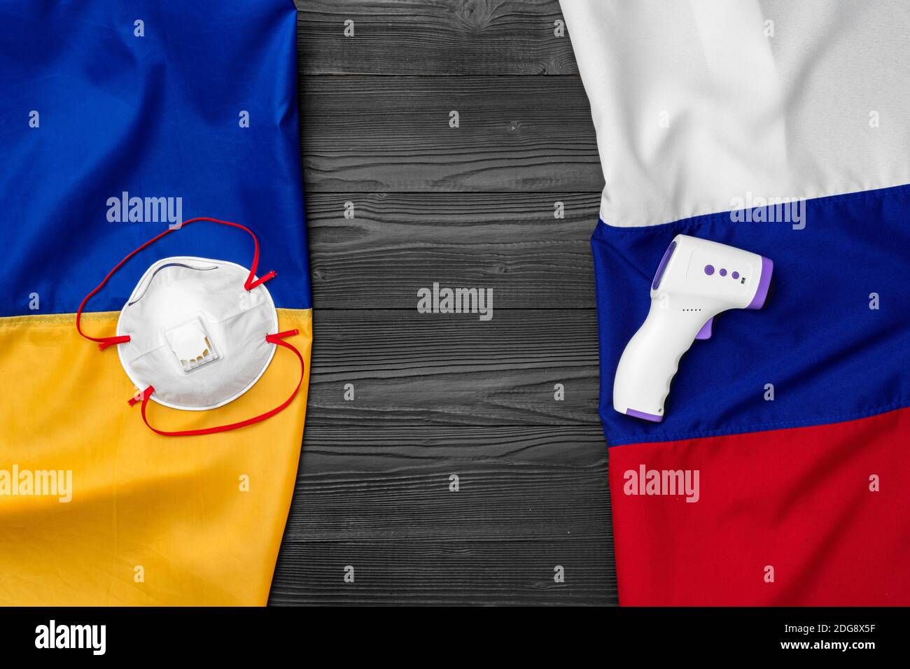 Flaggen von Russland und der Ukraine auf hölzernen Hintergrund mit medizinischen Masken Stockfoto