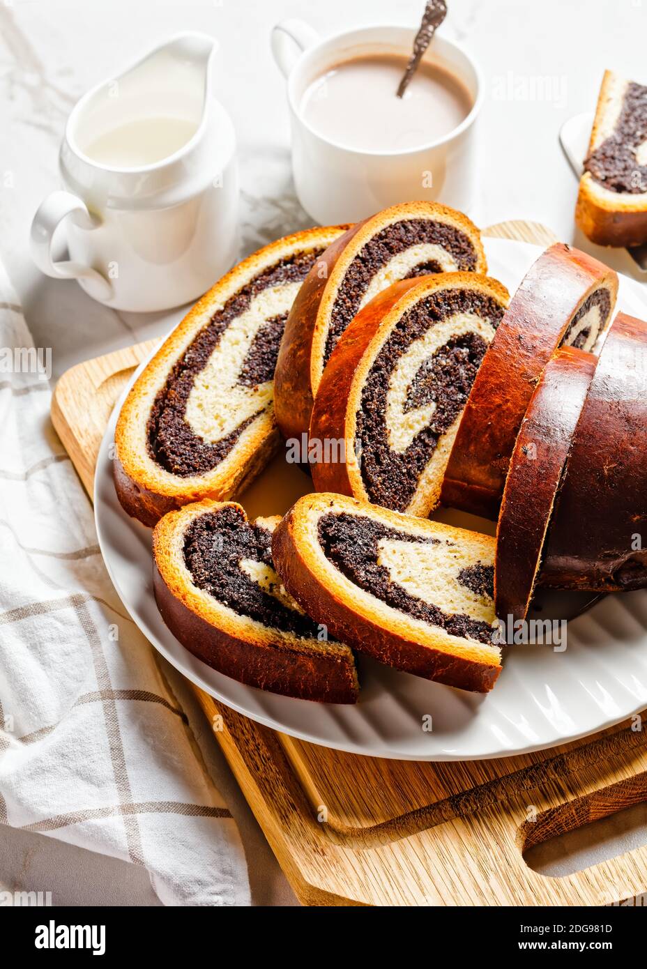 mohn Strudel auf einem weißen Teller mit heißem Kakao Getränk in einer Tasse auf einem Marmortisch, strudla od maka, kroatische Rezept, vertikale Ansicht von oben Stockfoto