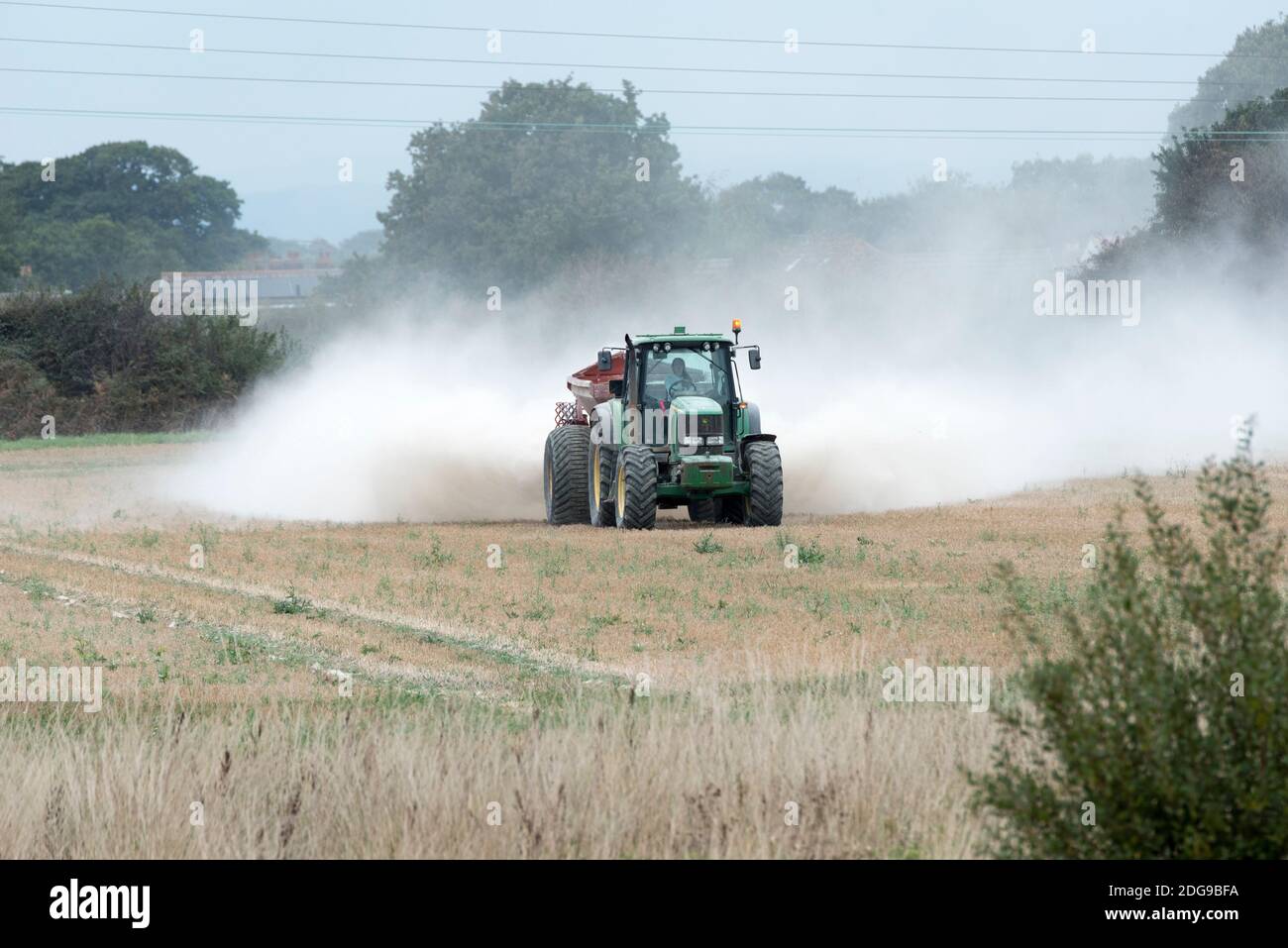 Ein John Deere Traktor verteilt Kalkdünger auf Ackerland in Hayling Island, Hampshire, Großbritannien Stockfoto