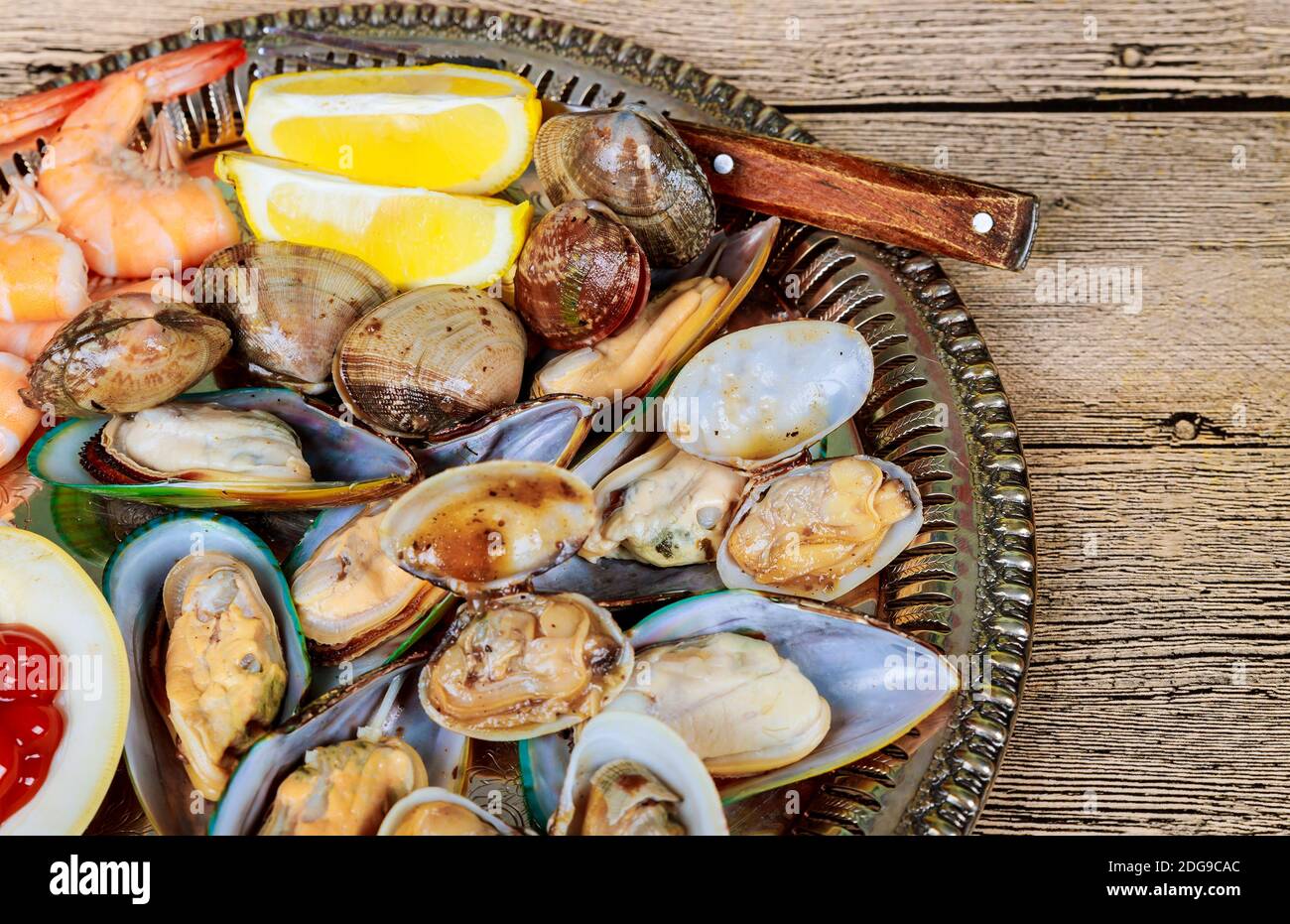 Metallschale mit grüner Miesmuschelsauce und Zitrone Stockfoto