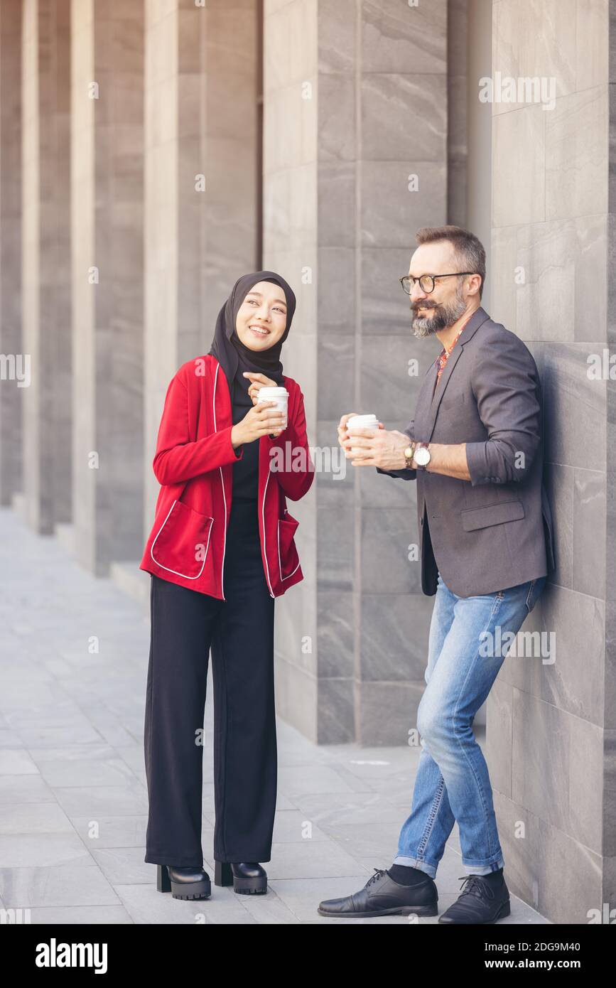 Schöner Bart mittleren Alters kaukasischen Geschäftsmann trinken Kaffee im Freien Café mit jungen schönen Hijab muslimischen Frauen Stockfoto