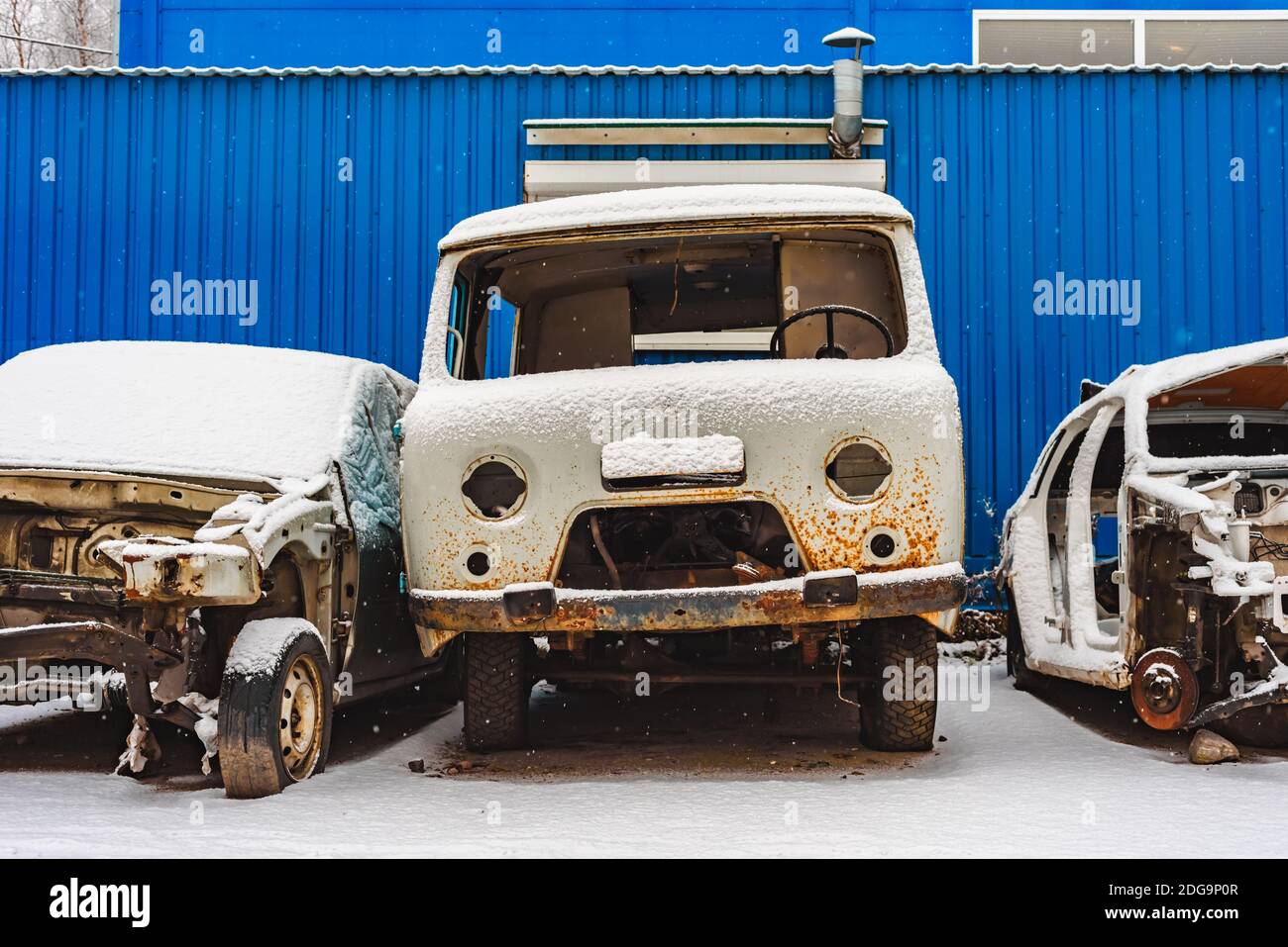 Die alten rostroten zerbrochenen Autos auf einer Müllhalde unter Schnee Stockfoto