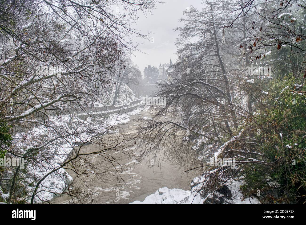Das schmutzige Wasser des Passers nach einem starken Schneefall und seine Uferpromenade in Meran, Italien, bedeckt von nassem Schnee. Stockfoto