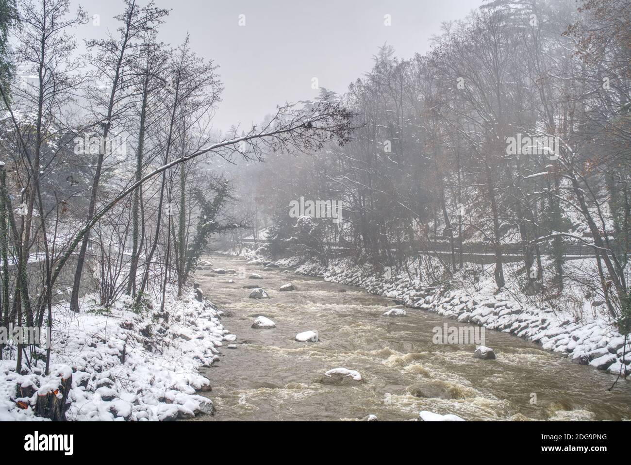 Das schmutzige Wasser des Passers nach einem starken Schneefall und seine Uferpromenade in Meran, Italien, bedeckt von nassem Schnee. Stockfoto