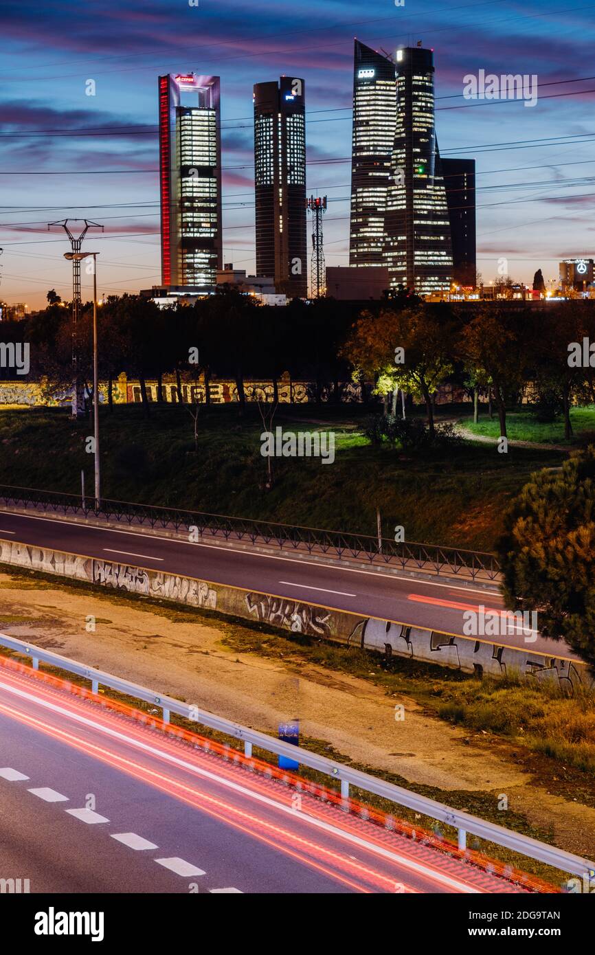 Cuatro Torres Business Area in Madrid Spanien mit Stromkabeln über sie mit Graffitis und Autobahn bei Sonnenuntergang. Blautöne. Stockfoto