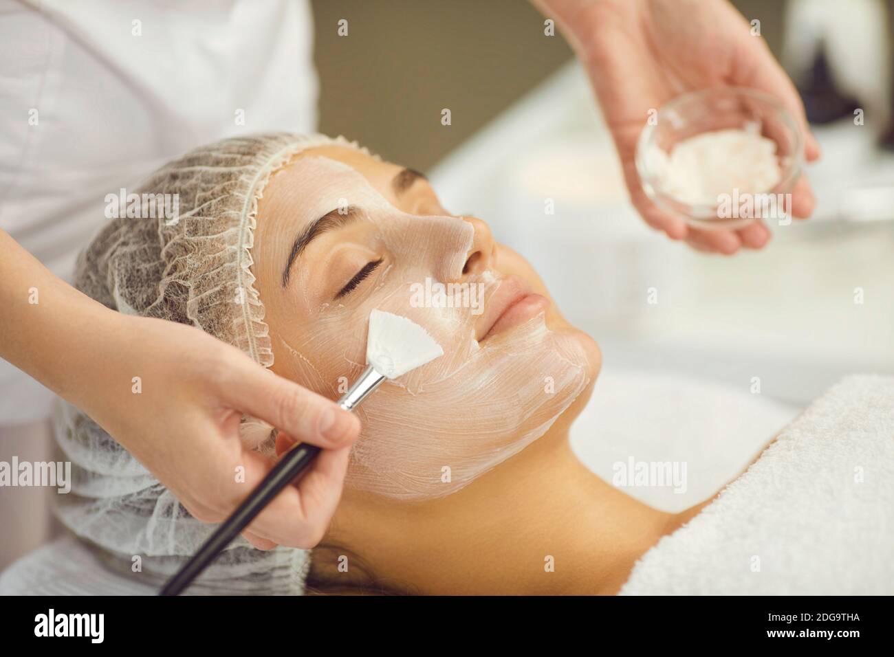 Entspannende Frauen Gesicht bekommen Verfahren der Anwendung feuchtigkeitsspendende Maske mit Bürste Stockfoto