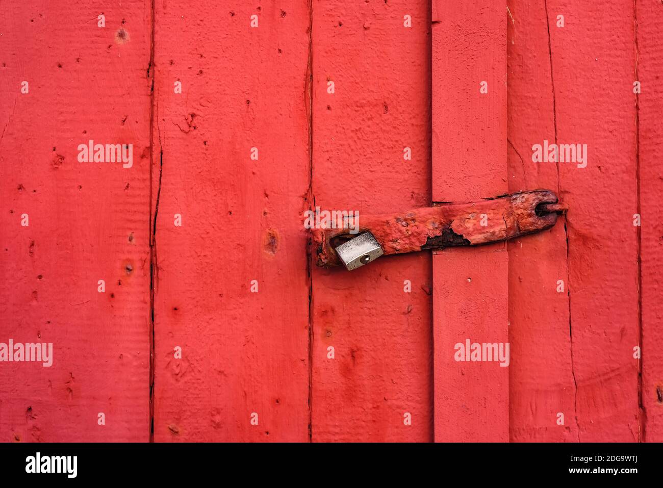 Großes Metallschloss, das an einer rot gestrichenen Tür hängt Stockfoto