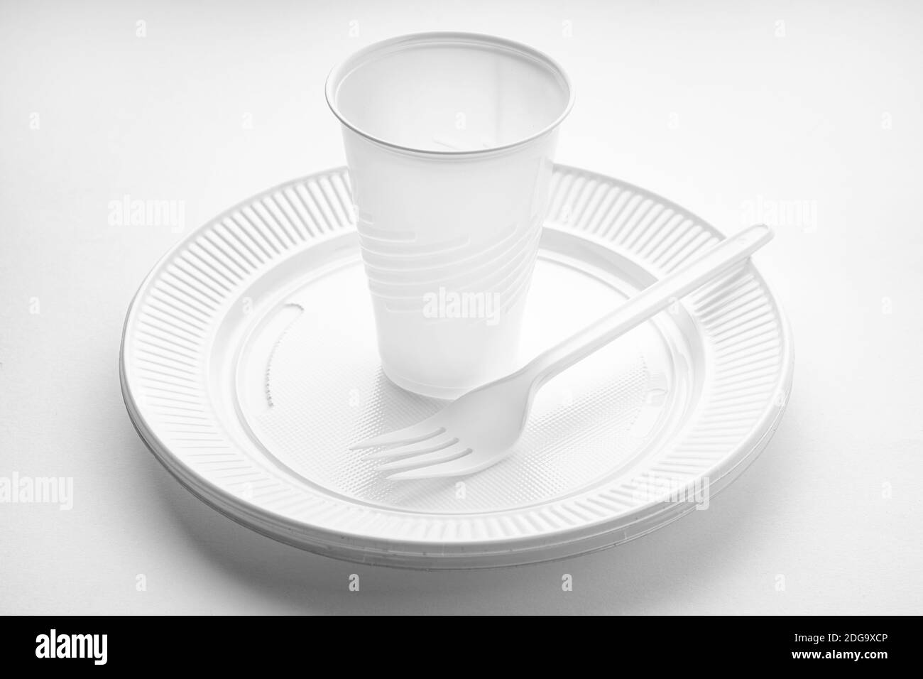 Geschirr aus Kunststoff. Weiße Vase, Teller und Gabel auf weißem Hintergrund. Einweg-Plastikmüll Stockfoto