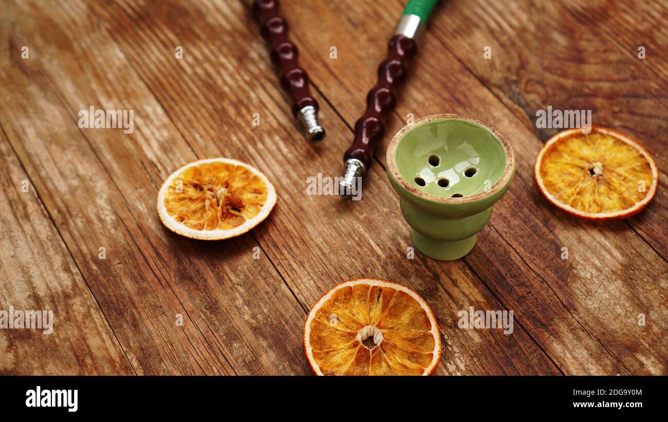 Shisha Schale auf Holzgrund mit trockenen Orangen und Shisha Rohre Stockfoto