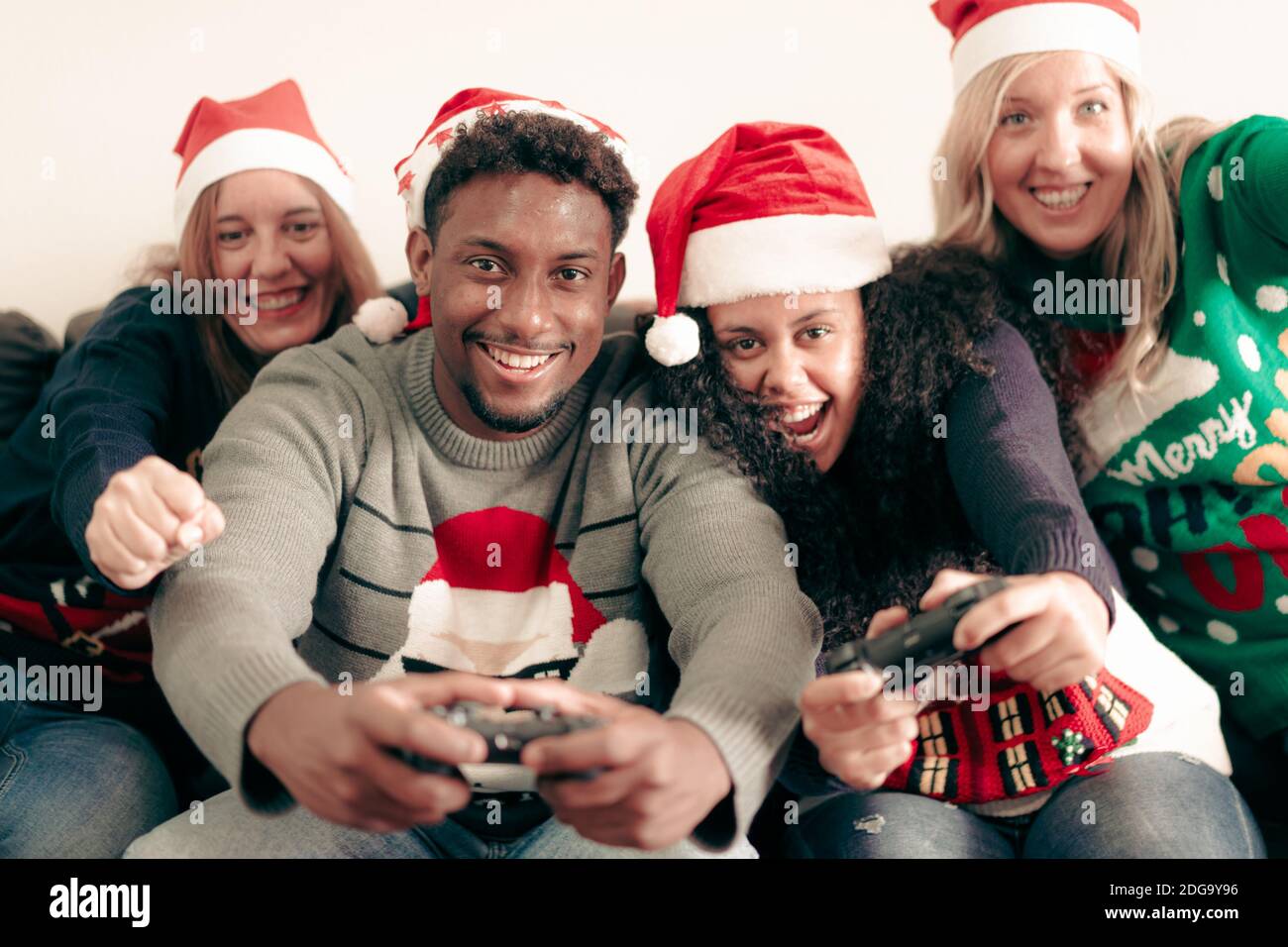 Millennial Menschen Spaß mit Videospielen Konsole auf weihnachten Zeit. Familie spielt den ganzen Tag Videospiele in der Wohnung. Weihnachten und Technolo Stockfoto