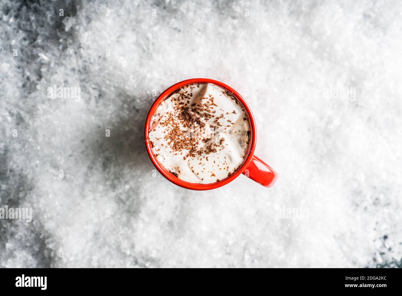 Rote Tasse mit heißer Schokolade und Marshmallow auf dem Kunstschnee mit rustikalem Holzhintergrund. Selektiver Fokus. Geringe Schärfentiefe. Stockfoto