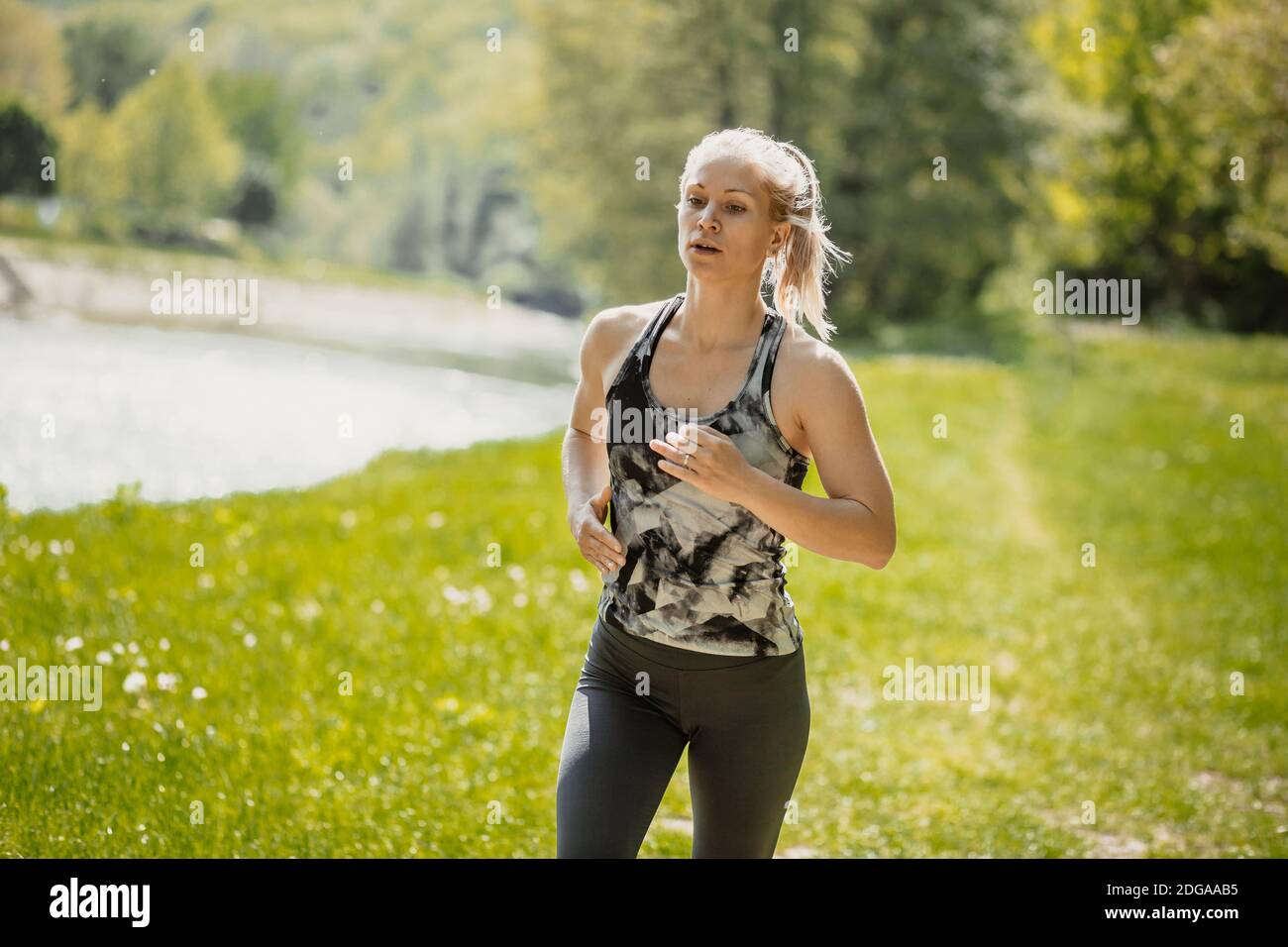 Foto von jungen blonden Mädchen läuft in der Natur, am Fluss am Morgen. Gesundes Lifestyle- und Sportkonzept Stockfoto
