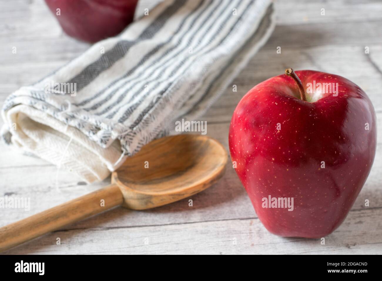 Roter Apfel auf einem Küchentisch mit Holzlöffel Stockfoto