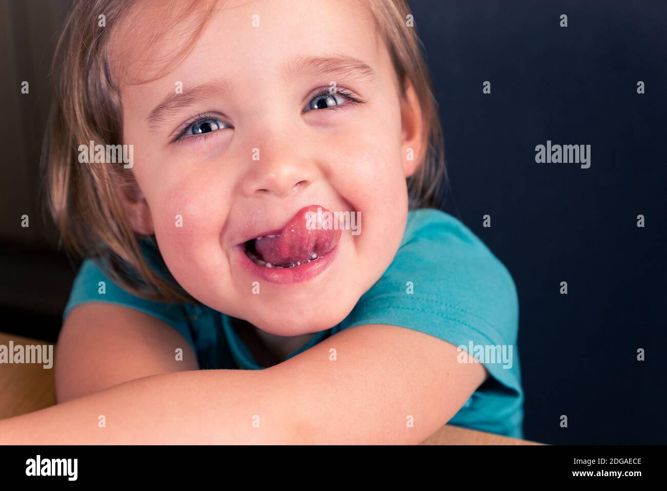 Nahaufnahme Porträt von fröhlich kaukasischen Kleinkind Mädchen zeigt Zunge, lustige Kinder Gesicht Stockfoto