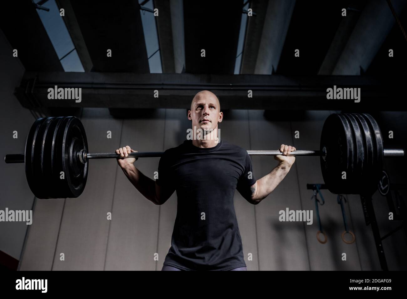 Athletic Muscular Man Halten Langhantel Auf Den Schultern In Der Turnhalle. Dramatische Farbkorrektur. Stockfoto