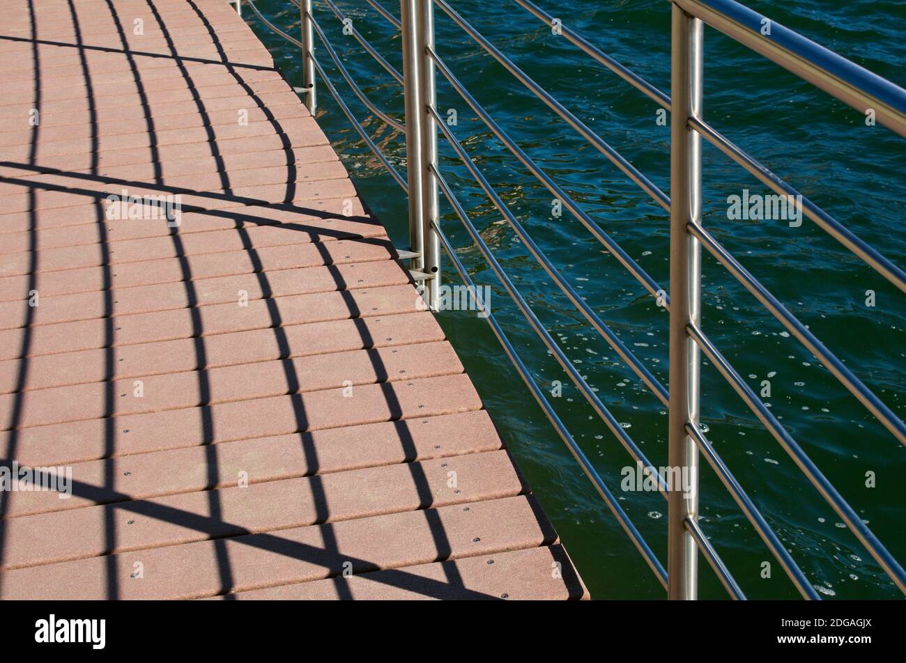 Schatten der Geländer auf Gehweg gegen den See Stockfoto