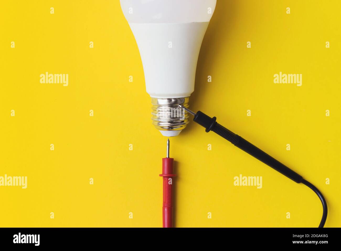 LED-Glühlampe mit Multimetersonden auf gelbem Hintergrund. Neue Technologie der Energie, Eco Power Konzept. Speicherplatz kopieren. Energiesparkonzept Stockfoto