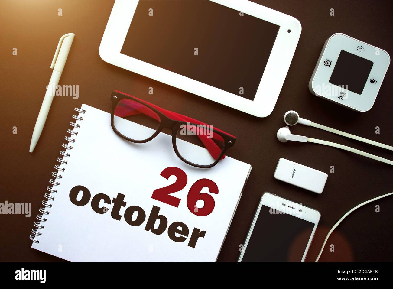 Oktober. Tag 26 des Monats, Kalenderdatum. Büroarbeitsplatz mit Laptop, Notebook, Bürobedarf und Schreibwaren auf brauner Rückseite. Herbst Monat, Tag Stockfoto