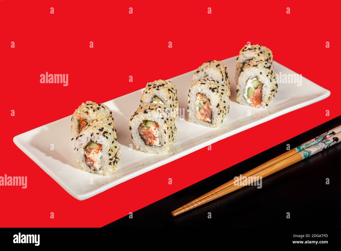 Sushi setzt Nigiri, Uramaki, California, Philadelphia, auf einen weißen Teller. Auf einem roten Hintergrund. Speicherplatz kopieren. Stockfoto