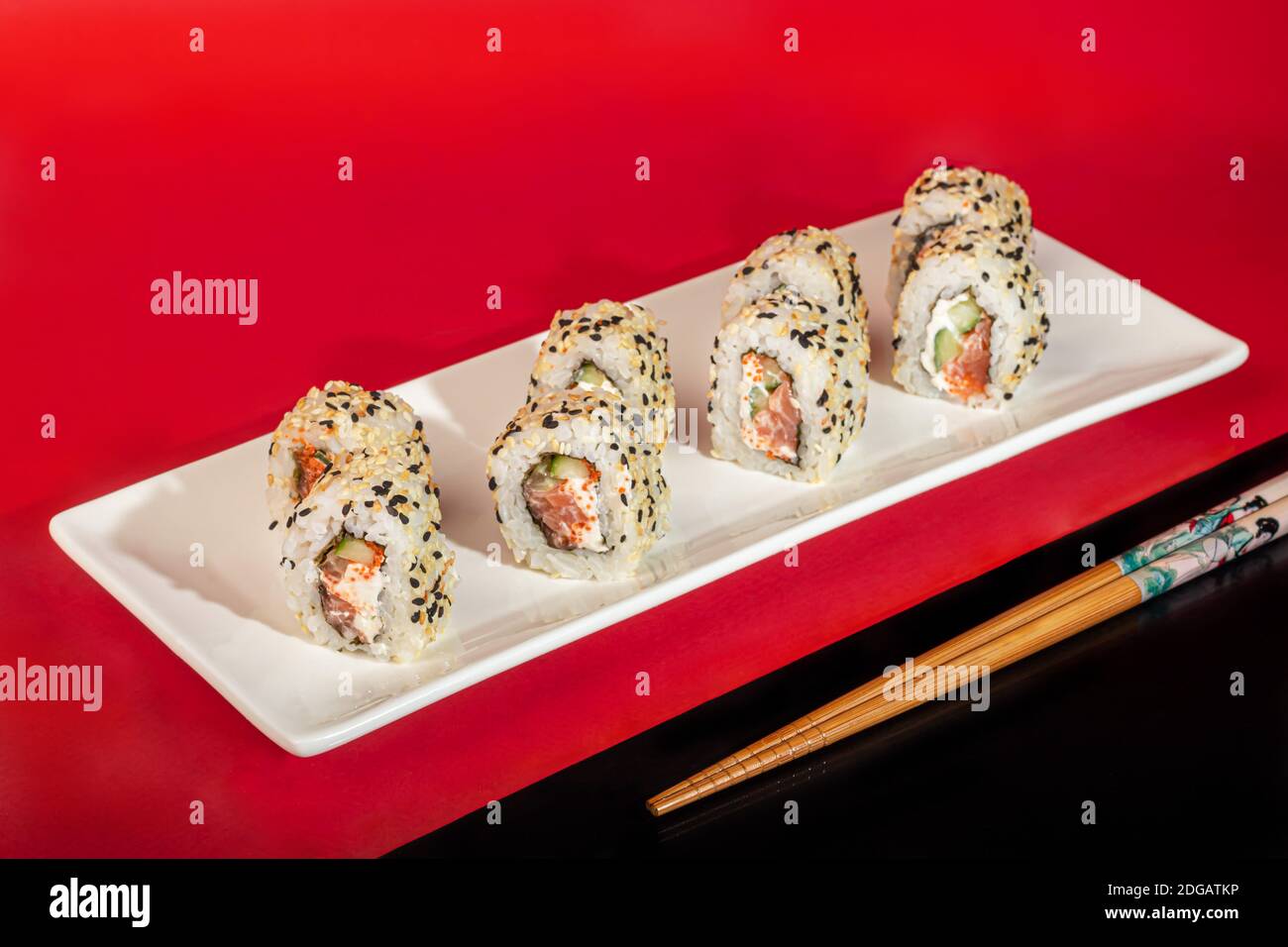Sushi setzt Nigiri, Uramaki, California, Philadelphia, auf einen weißen Teller. Auf einem roten Hintergrund. Speicherplatz kopieren. Stockfoto