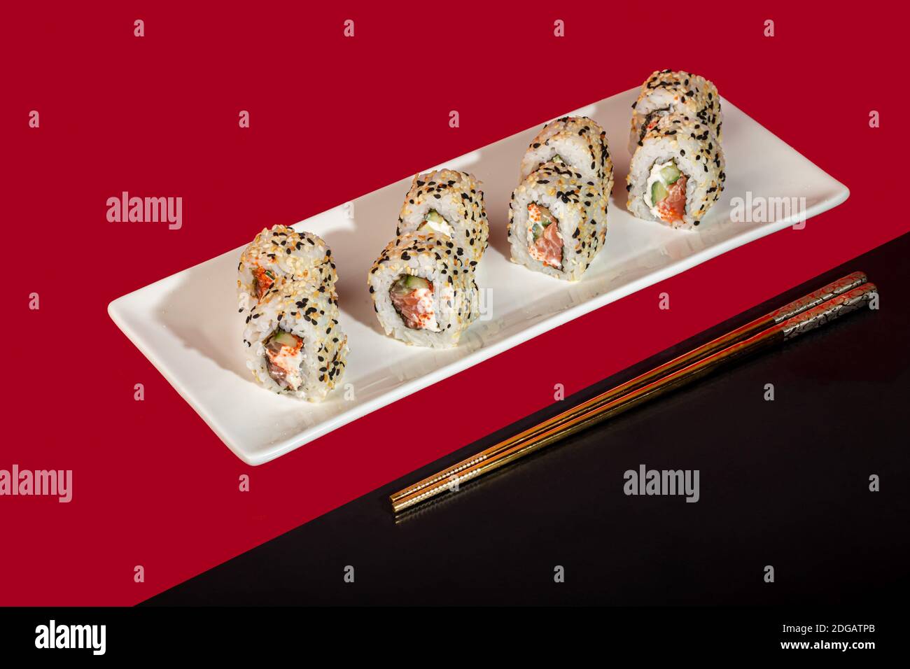 Sushi setzt Nigiri, Uramaki, California, Philadelphia, auf einen weißen Teller. Auf einem roten Hintergrund. Speicherplatz kopieren. Stockfoto