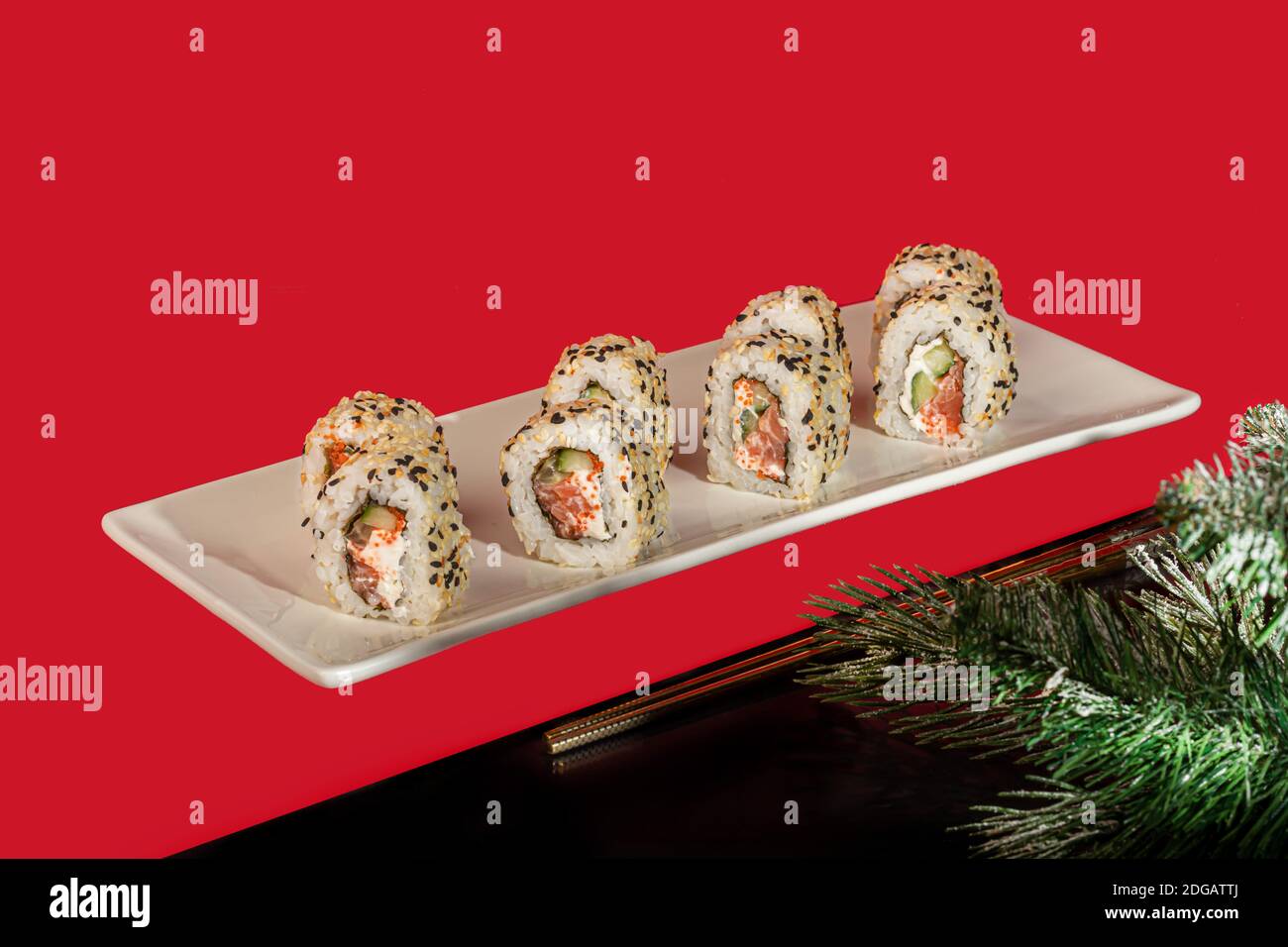 Sushi setzt Nigiri, Uramaki, California, Philadelphia, auf einen weißen Teller. Auf einem roten Hintergrund. Speicherplatz kopieren. Stockfoto