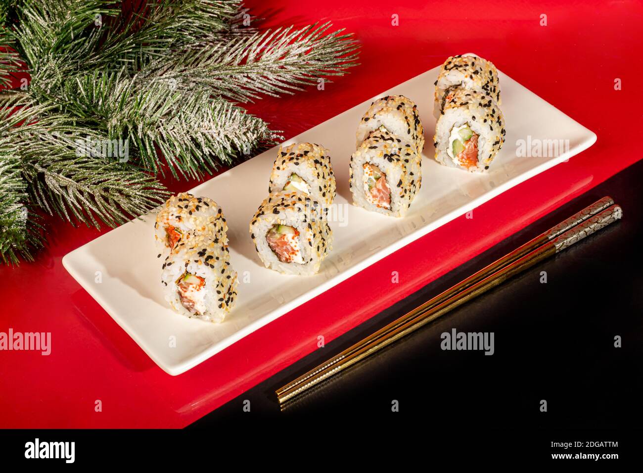 Sushi setzt Nigiri, Uramaki, California, Philadelphia, auf einen weißen Teller. Auf einem roten Hintergrund. Speicherplatz kopieren. Stockfoto