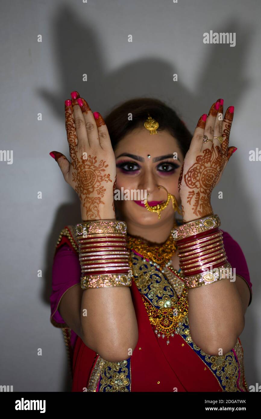 Ein schönes indisches Mädchen in Brautkleid trägt roten Saree Und Gold Ornamente zeigen Tattoo genannt mehindi Stockfoto
