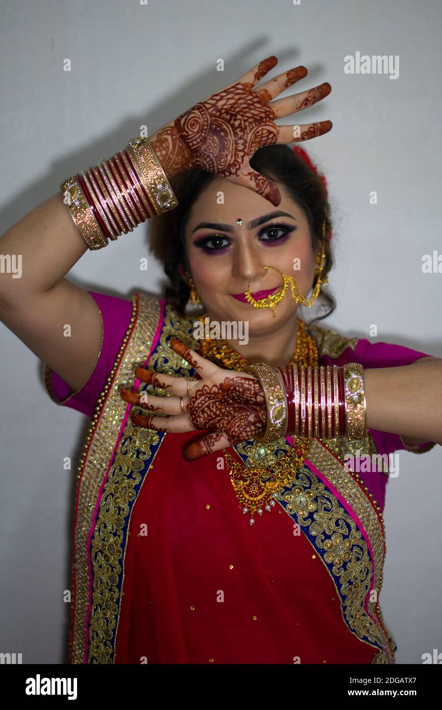 Ein schönes indisches Mädchen in Brautkleid trägt roten Saree Und Gold Ornamente zeigen Tattoo genannt mehindi Stockfoto